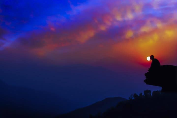 meditation monk sitting on a rock at sunrise