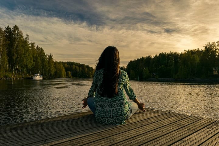 girl meditating at the lake