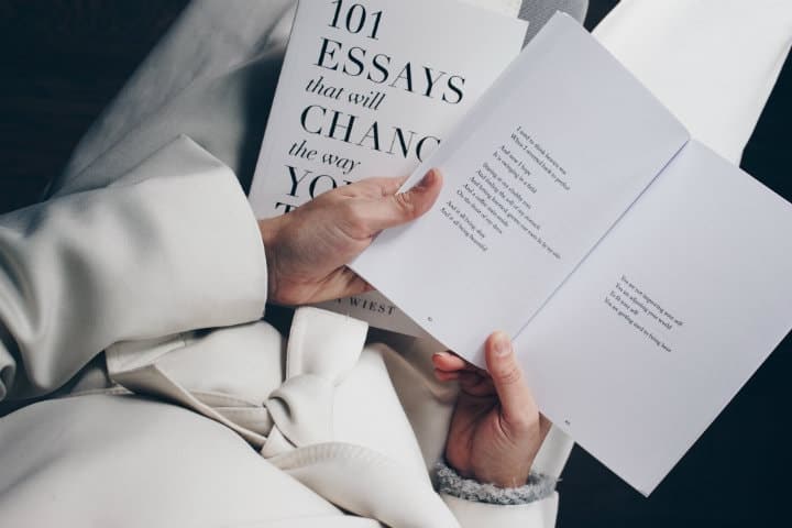 a woman dressed in white holding a book with essays and poems