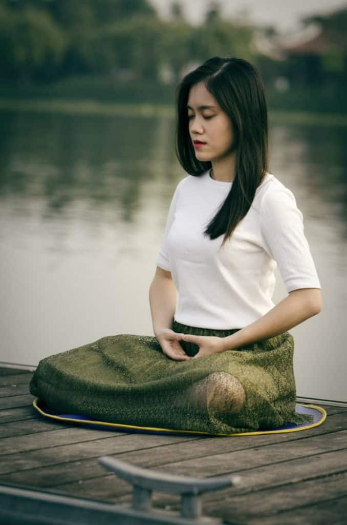 young woman meditating near to a lake