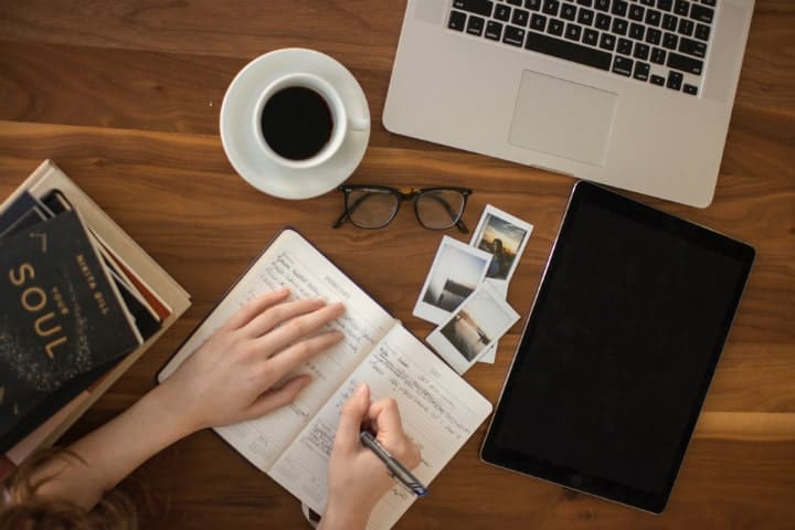 person holding a pen writing in a notebook