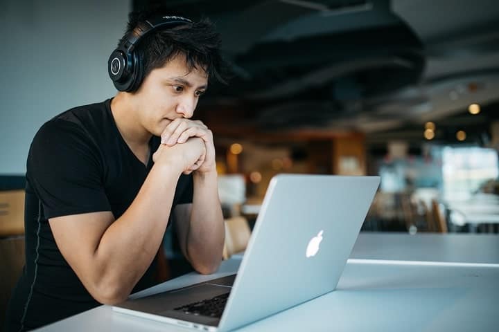 man in a library studying with mac and headphones