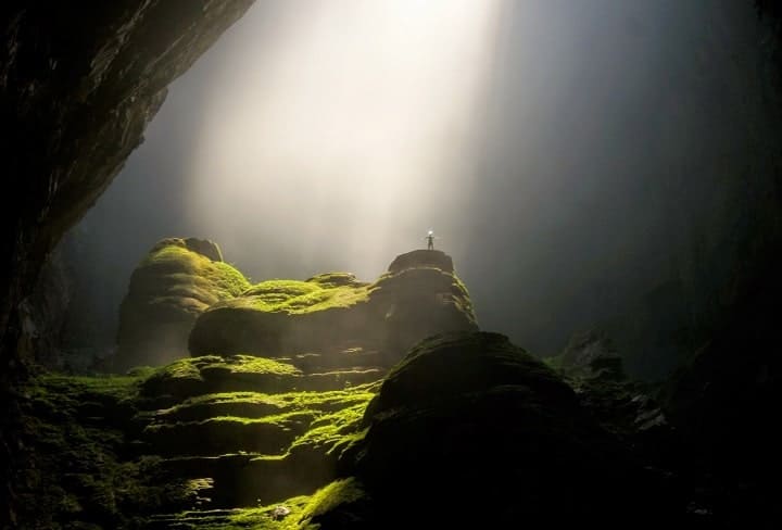 person in a large cave standing in awe