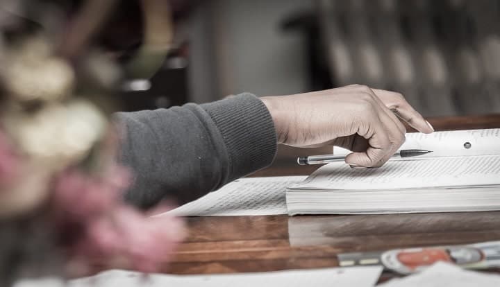 person putting a pen on a book