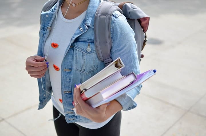 student girl holding a stack of books and papers