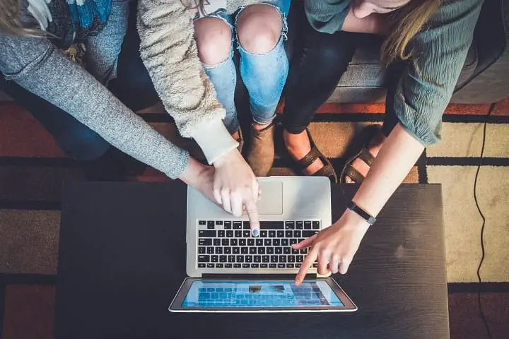 students pointing at a laptop