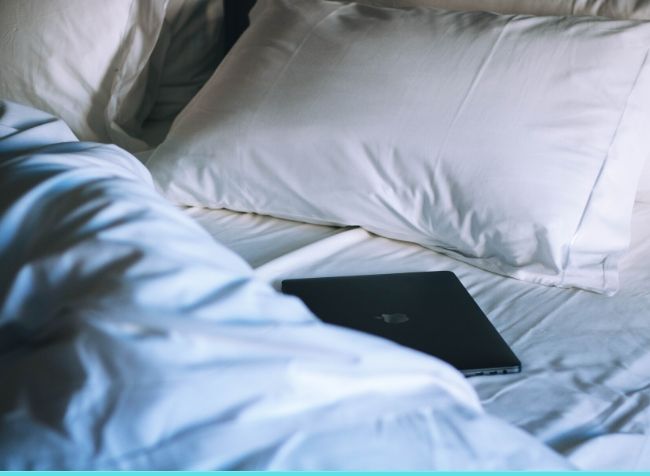 tablet lying on a bed with pillow in the background - featured image