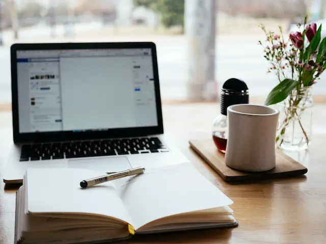 laptop, pen, and notebook on a wooden table