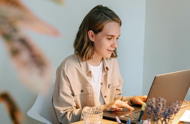 young writer writing at a desk on a laptop