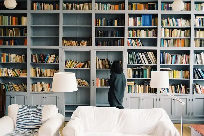 Girl perusing huge shelves of books in an apartment