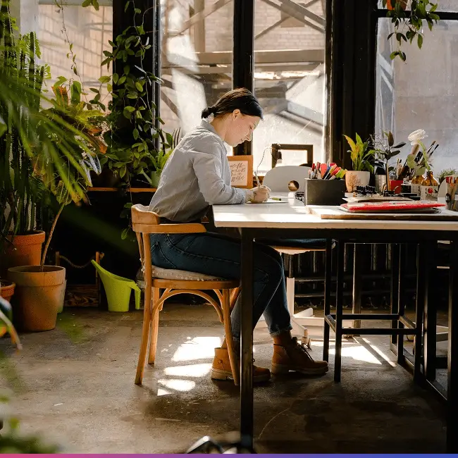 woman writing at a beautiful desk surrounded by plants