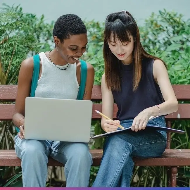 students writing in a a notebook and on a computer