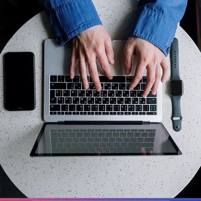 typing on a laptop keyboard with watch and phone