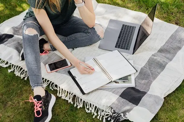 young woman writing in the park