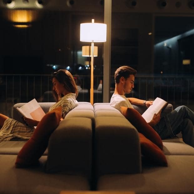 man and woman reading with a reading lamp in the evening