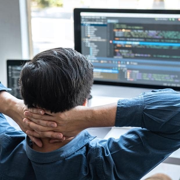 male programmer looking at code on computer screen