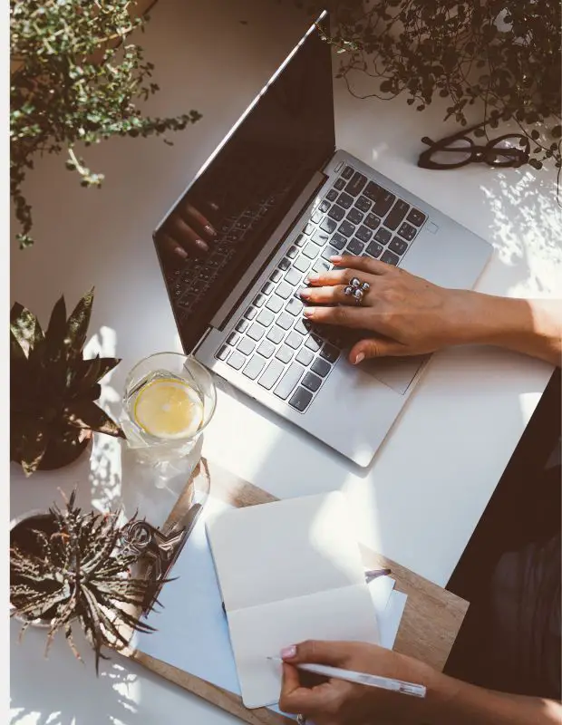 Person writing with a laptop and a notebook