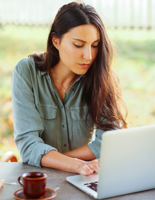 Young beautiful female, using a laptop and drinking coffee