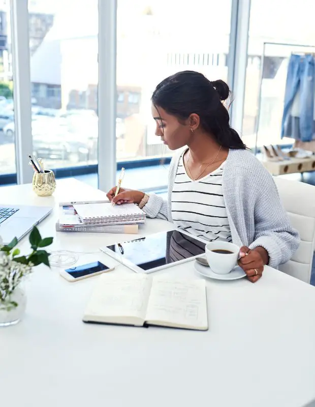 Young female blogger writing down ideas in a notebook