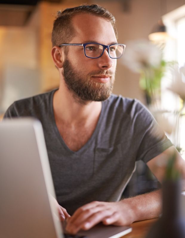 Young male blogger with eyeglasses writing with a laptop