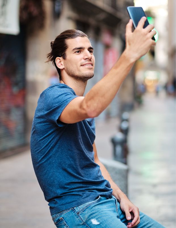Young male influencer holding a phone in a city street