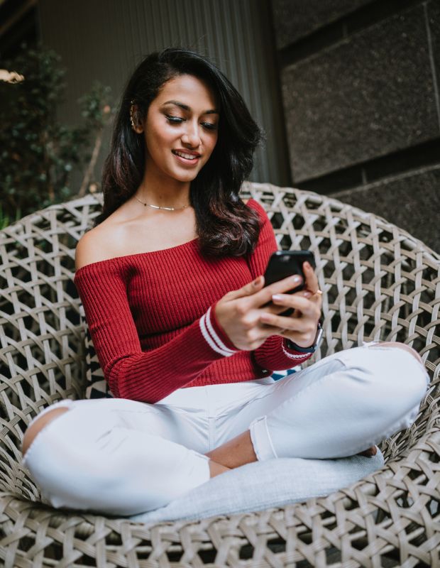 beautiful young woman in red sweater looking at her mobile phone