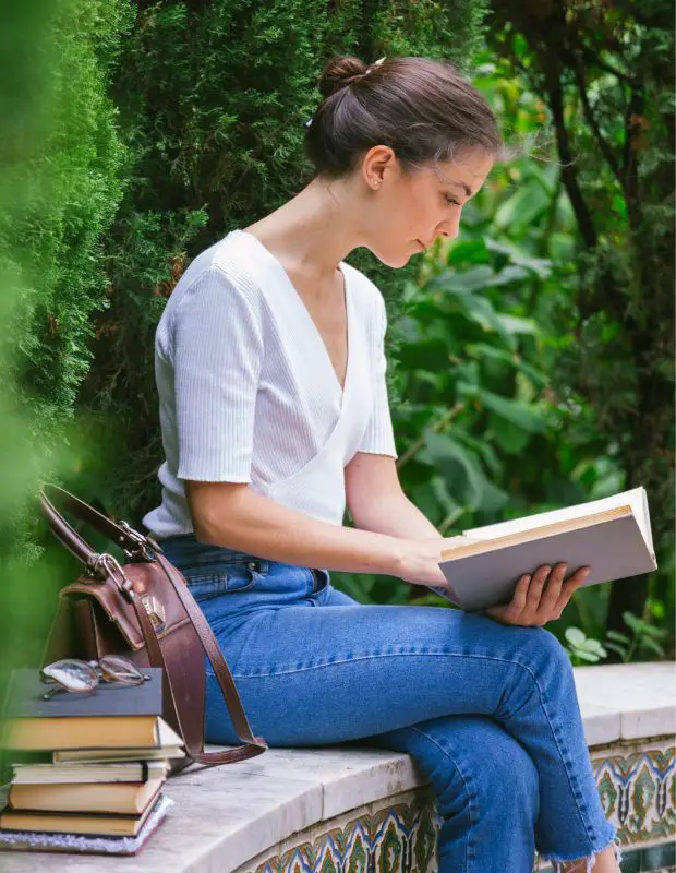female student reading books in a park