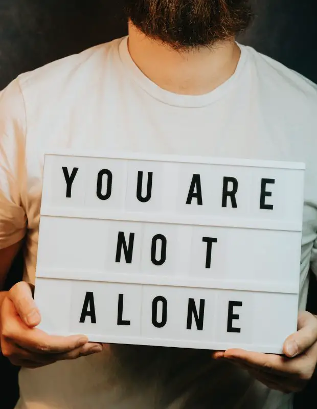 a man holding a you are not alone sign