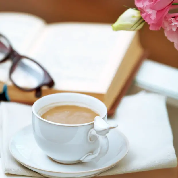 a book, glassess, coffe, and a flower