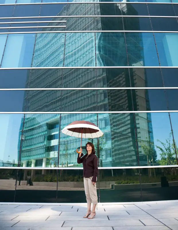 a woman standing with an umbrella in front of corporate building