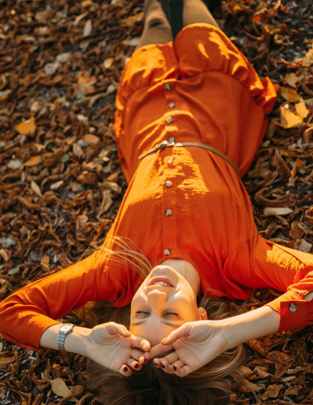 a young woman laying on the ground in an orange dress