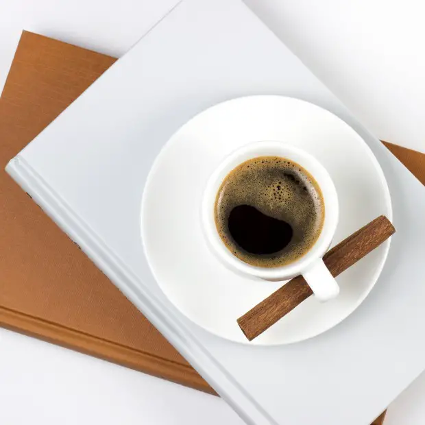 two plain cover books and a coffee on a table