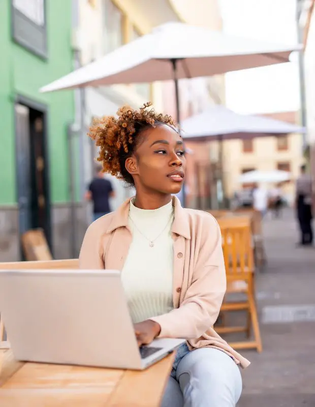 a beautiful woman of color writing in an outdoor cafe