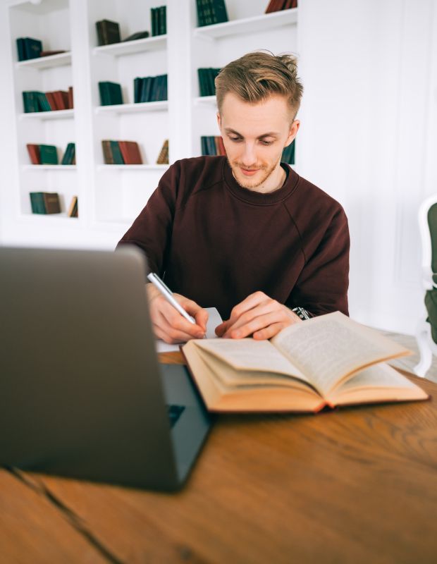 a male student working on an essay in a library setting