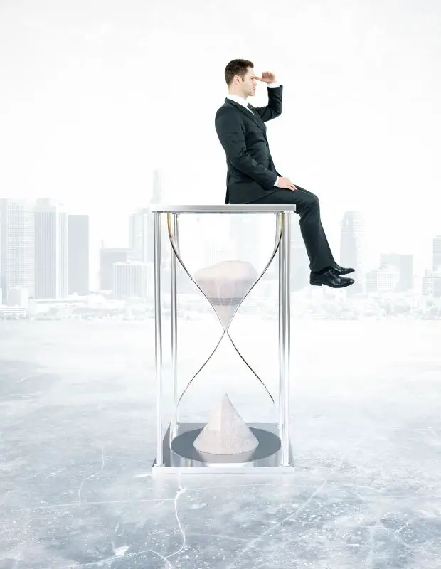 a man dressed in suit sitting on a huge hourglass