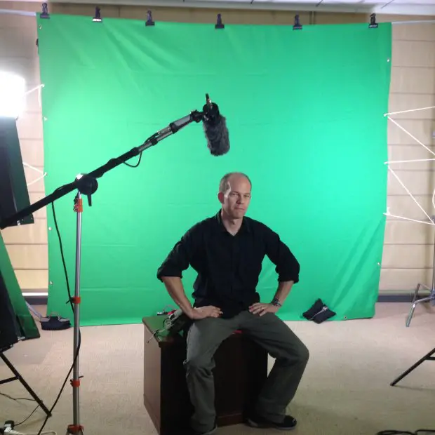 a man sitting in front of a green screen